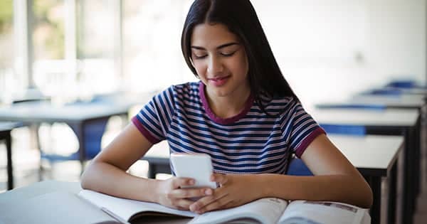 Student studying while using mobile phone